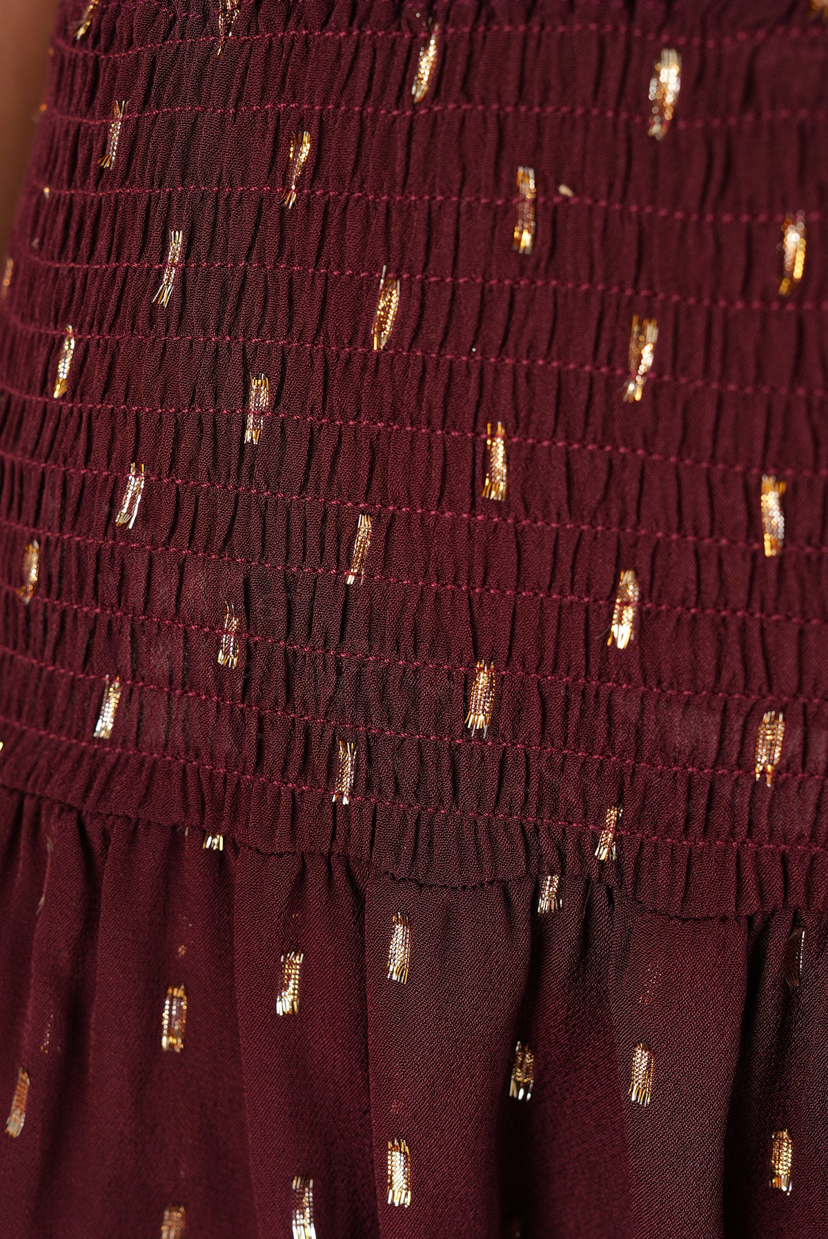 Detalle de la cintura fruncida de la falda color vino con hilos dorados